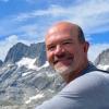 Shawn's headshot. Smiling with mountains in background.