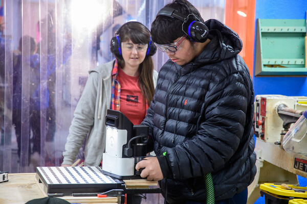two teenagers wearing ear protection and using machinery