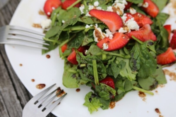 strawberry spinach and feta salad on a white plate