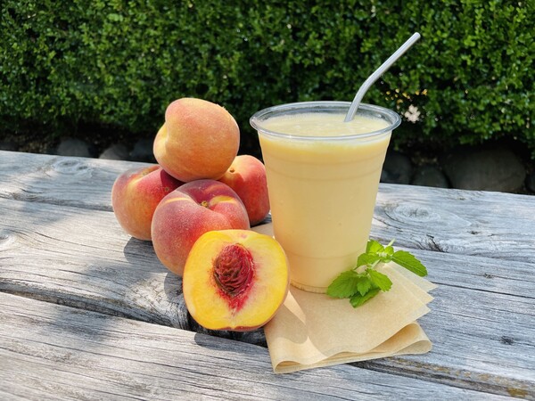 peach smoothie with fresh peaches and mint on a wooden table