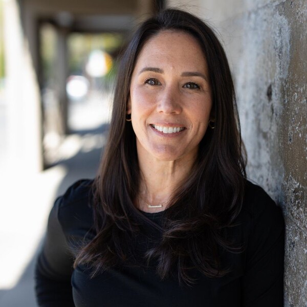 Board member Elizabeth Walsh leaning against a wall wearing a black shirt
