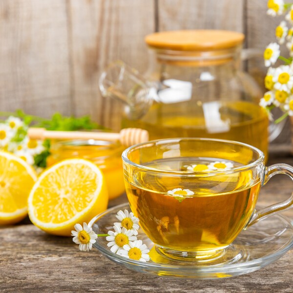 chamomile tea in a clear cup with lemons in the background